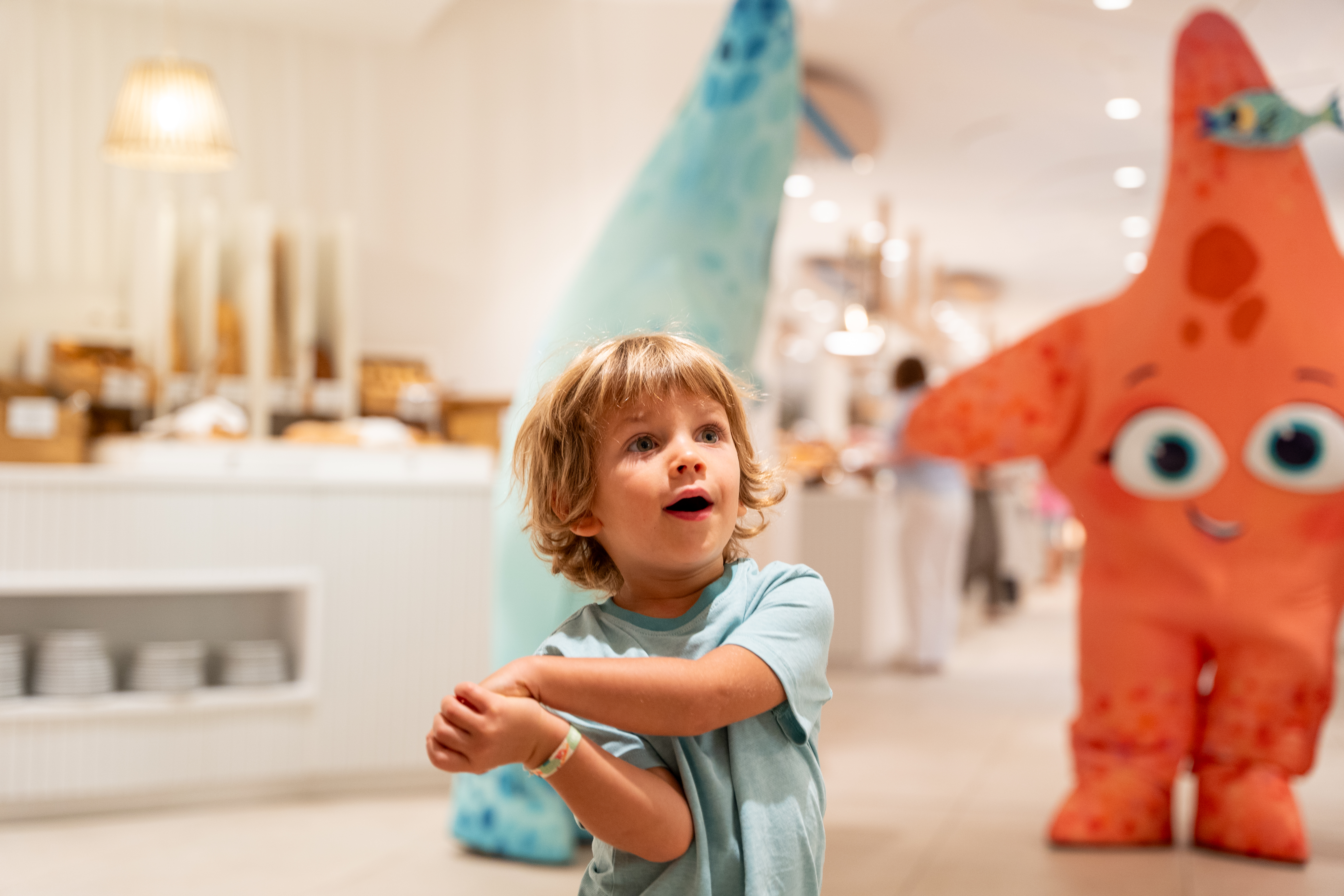 Child Posing Indoors With Cartoon Mascots Nearby