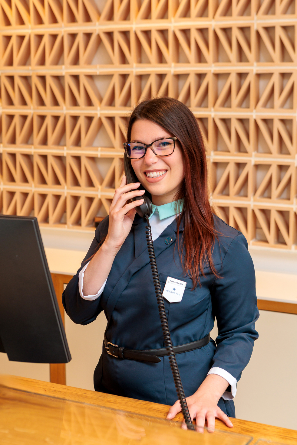 Smiling hotel receptionist speaking on telephone