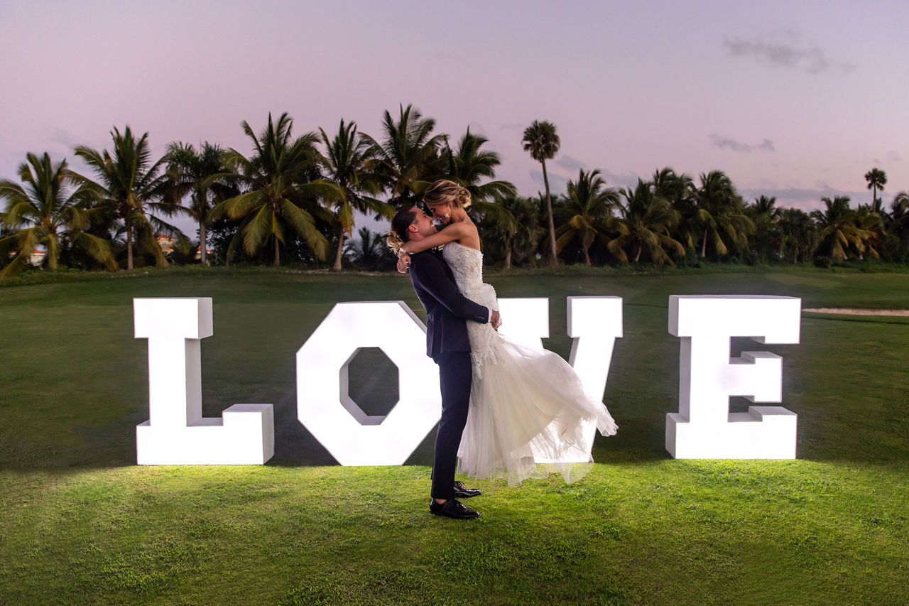 Bride and groom embracing by LOVE sign